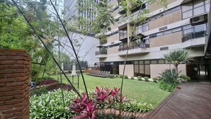 A multi-story building with balconies, a courtyard with greenery, and a wooden deck. - Fully Furnished Apartments in a Building With a Pool Just a few Meters From Av. Paulista Tnps (São Paulo)