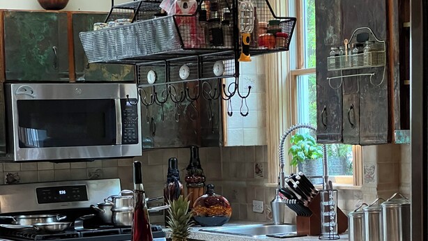 A modern kitchen with stainless steel appliances, a central island, and a dining area with a glass table and metal chairs. - Charming 1-bedroom apartment - 38 Mins to NYC / Parking on site (New Rochelle)