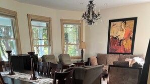 A spacious living room with a dining area, a large sofa, a television, and a chandelier. - Charming 1-bedroom apartment - 38 Mins to NYC / Parking on site (New Rochelle)