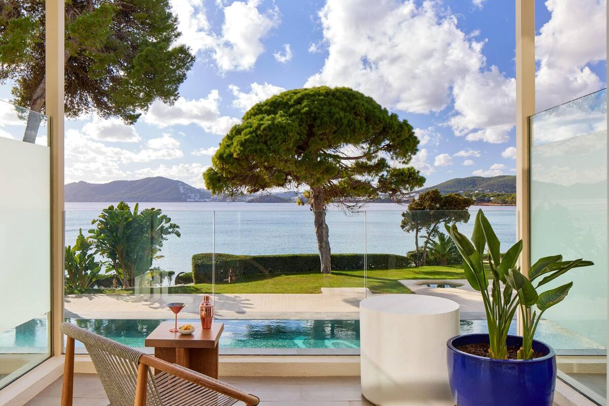 Un balcon moderne offrant une vue dégagée sur un lac, une pelouse bien entretenue et un grand arbre.