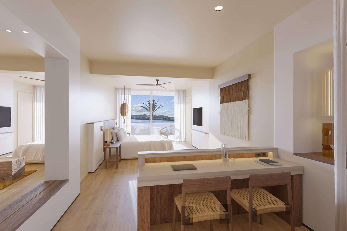 Une chambre d’hôtel moderne dotée d’une grande fenêtre, d’un coin repas avec une table et des chaises en bois, et offrant une vue sur l’extérieur.