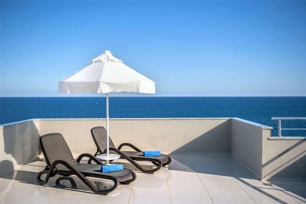 A balcony with two lounge chairs and a white umbrella, overlooking the sea. - Porto Bello Hotel Resort & Spa (Antalya)