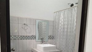 A small, compact bathroom with a toilet, sink, and shower. - Apartamento #3 (Macario Gómez)