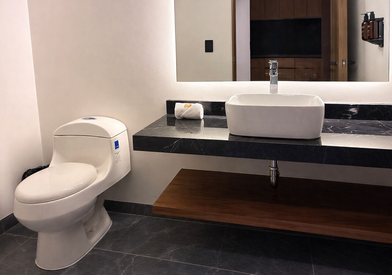 A modern bathroom with a toilet, a sink, and a mirror.