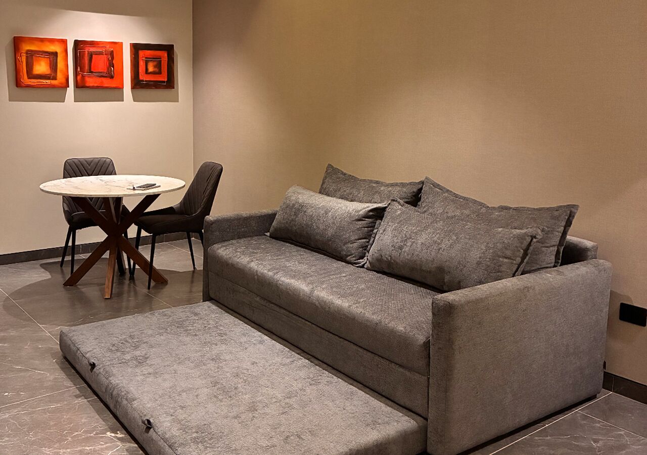 Ein modernes Wohnzimmer mit einem grauen Sofa, einem kleinen runden Tisch und zwei Stühlen.