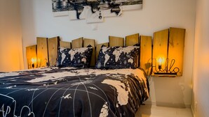 Une chambre à coucher avec un grand lit, une tête de lit en bois et une œuvre d’art représentant une carte du monde au-dessus.