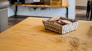 Una sala de estar con una mesa de centro de madera, una cesta de mimbre y un televisor montado.