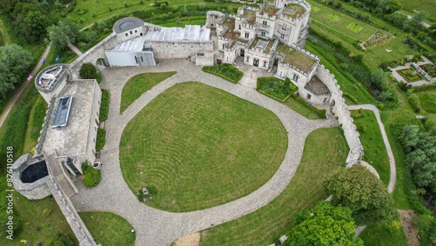Vista aérea de un castillo histórico con un amplio césped central, jardines circundantes y un foso.