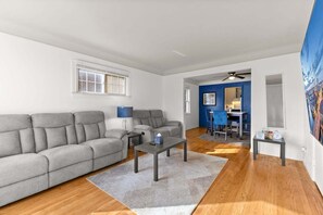 A modern living room with a grey sofa, a coffee table, and a blue accent wall. -  2BR Detroit Getaway – 1 Block from Joe Louis Greenway and 5 Miles to Downtown (Detroit)