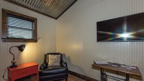 Una habitación con un escritorio de madera, una silla de cuero, una lámpara, una máquina de coser y un televisor.