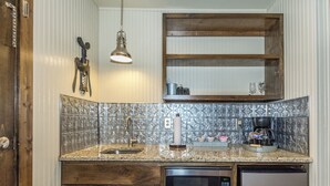 Una cocina compacta con microondas integrado, cafetera y lavamanos.