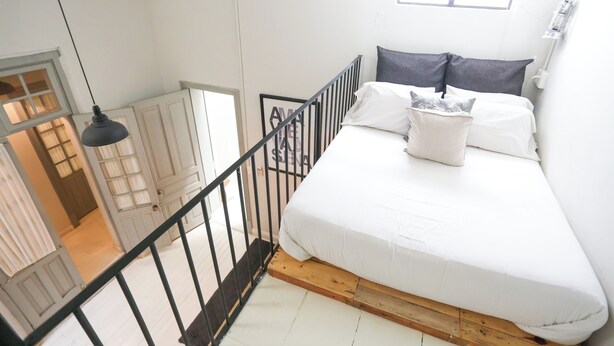 Um quarto com uma cama, uma janela e uma escada.