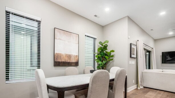 A dining area with a table and chairs, a plant, and a TV in the background. - Just Listed, D Town Views, OSU, Short North! (Columbus)