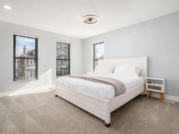 A modern bedroom with a large bed, white walls, and a view through the window. - High End New Build, Rooftop Hot Tub, City Views! (Columbus)