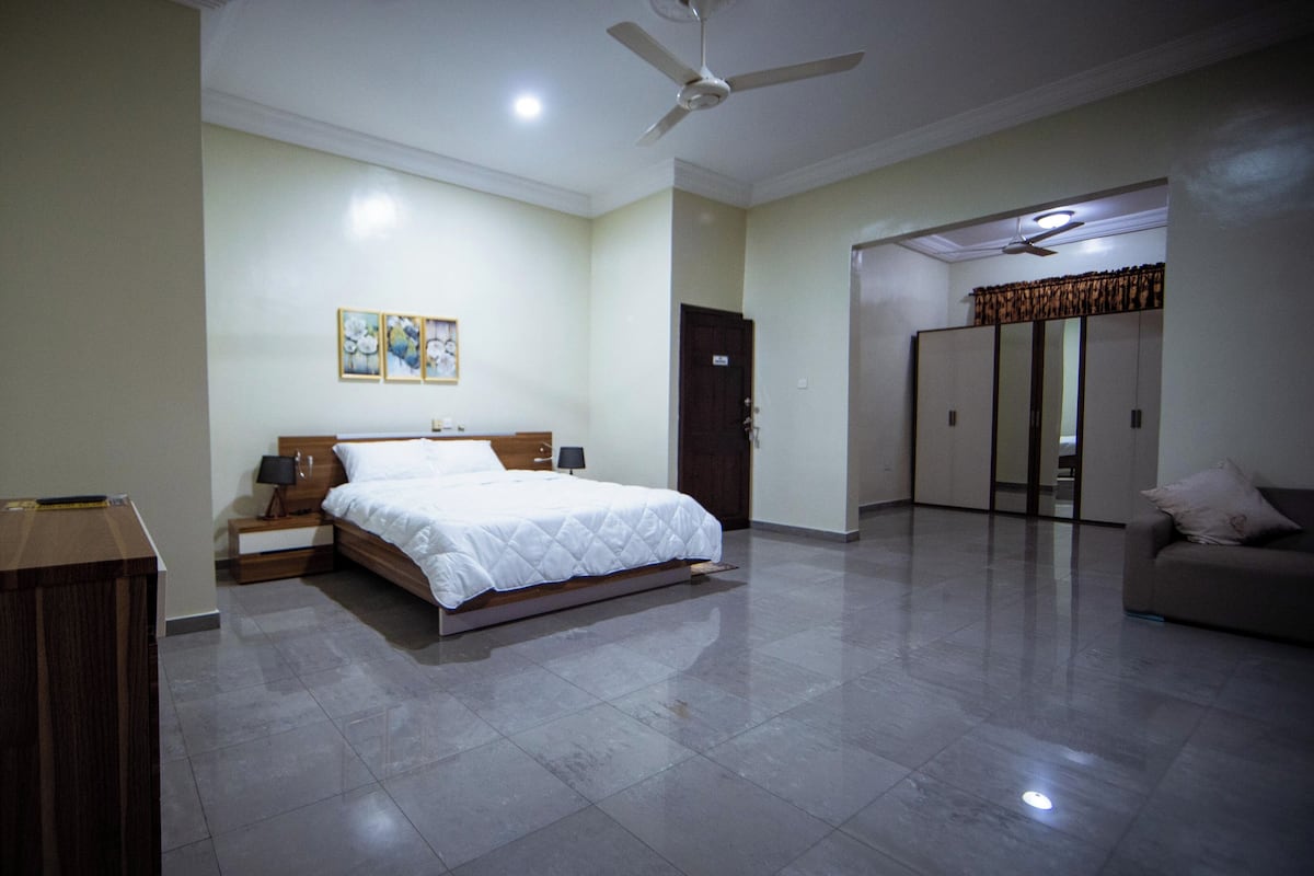 A hotel room with a bed, bedside table, lamp, and a ceiling fan.
