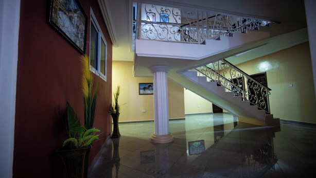 A spacious lobby with a grand staircase, marble flooring, and decorative columns. - Private Home Lodge (Accra)