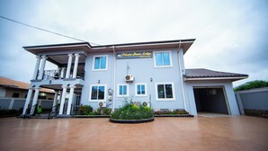 A two-story house with a balcony, a sign reading "Private Home Lodge," and a front garden. - Private Home Lodge (Accra)