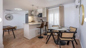 A modern kitchen with a central island, pendant lighting, and a dining area with a table and chairs. - Al Andalus: Chic, Serene & Posh City Center Pad! (Granada)