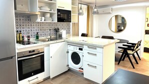 Una cocina compacta equipada con lavadora, microondas y horno integrado.