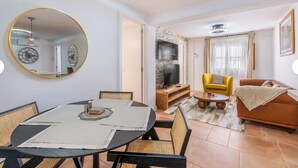 Una sala de estar moderna con comedor, un sofá amarillo y un televisor.