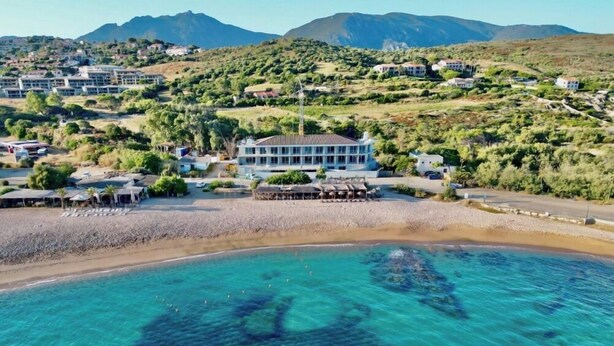 A coastal hotel with a beach view, clear blue waters, and a hilly landscape in the background. - Casa C (Propriano)