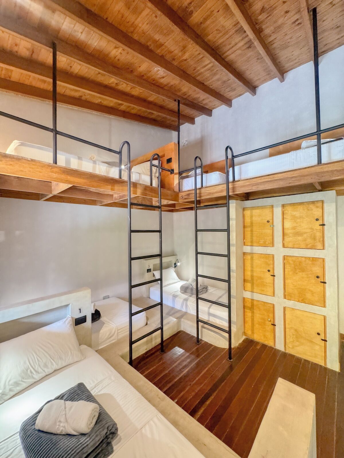 A bunk bed room with wooden beams and metal ladders.