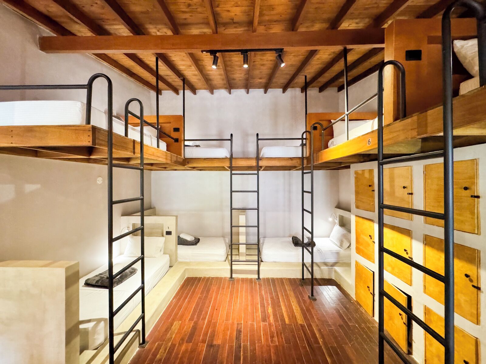 Habitació amb lliteres, bigues de fusta, una escala i armaris d'emmagatzematge.