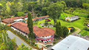 A hotel with multiple buildings, a central courtyard with seating, and lush greenery surrounding the property. - Dreamer Cocora (Salento)