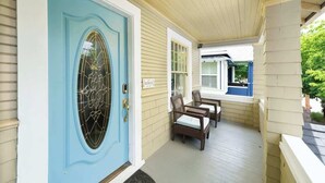 A porch with a light blue door, wicker chairs, and a small table. - 3 BR 1 BA - Cozy Home - Walkscore 97 - Shopping (Portland)