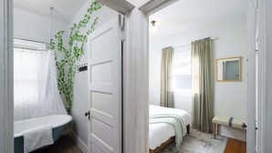 A bedroom with a bed, a bedside table, a mirror, and a window with curtains. - 3 BR 1 BA - Cozy Home - Walkscore 97 - Shopping (Portland)