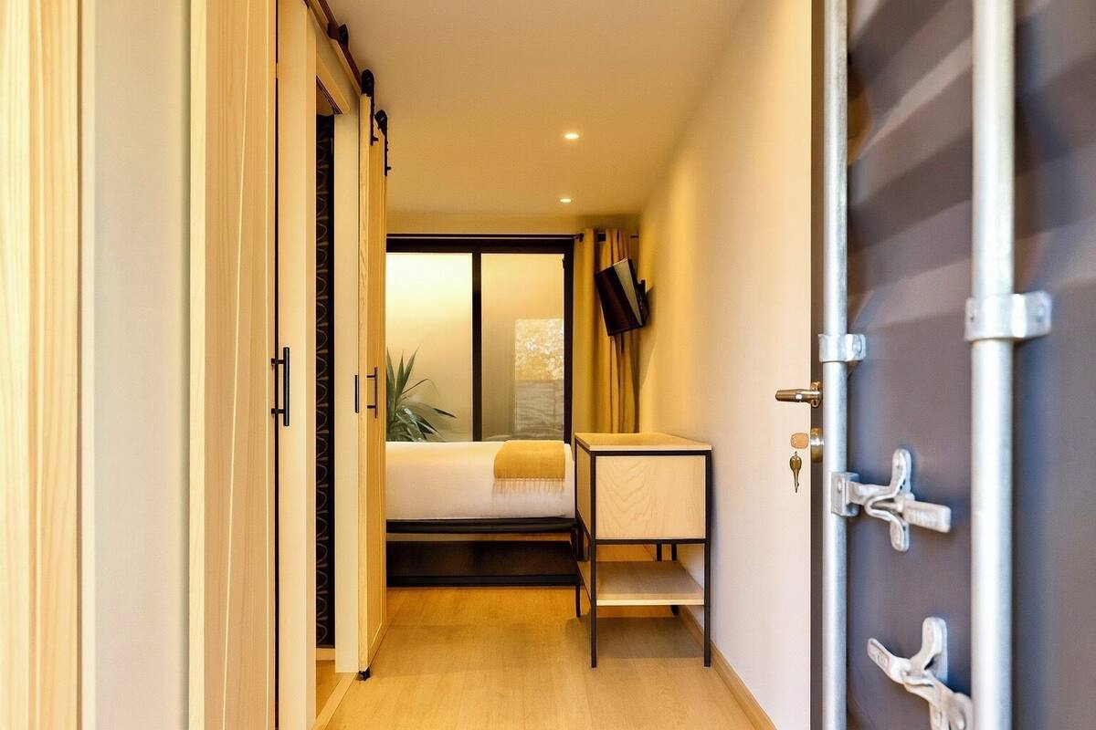 A hotel room with a bed, a small table, a TV, and a sliding door.