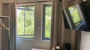A room with a desk, a TV, a coffee maker, and a bottle of water. - Casa Marina (Querétaro)