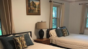 Ein Hotelzimmer mit zwei Betten, einem Bild an der Wand und einem Fenster mit Vorhängen.