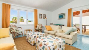 Ein Wohnzimmer mit einer Couch, zwei Sesseln, einem Couchtisch und einem Esstisch.