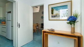 Eine moderne Küche mit weißen Schränken, einem Kühlschrank und einem Essbereich mit Stühlen und einem Tisch.