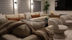 A modern living room with a sofa, armchairs, a flat-screen TV, and a plant. - Modern Waterfront home w/ Game Room & Private Dock (Cape Coral)
