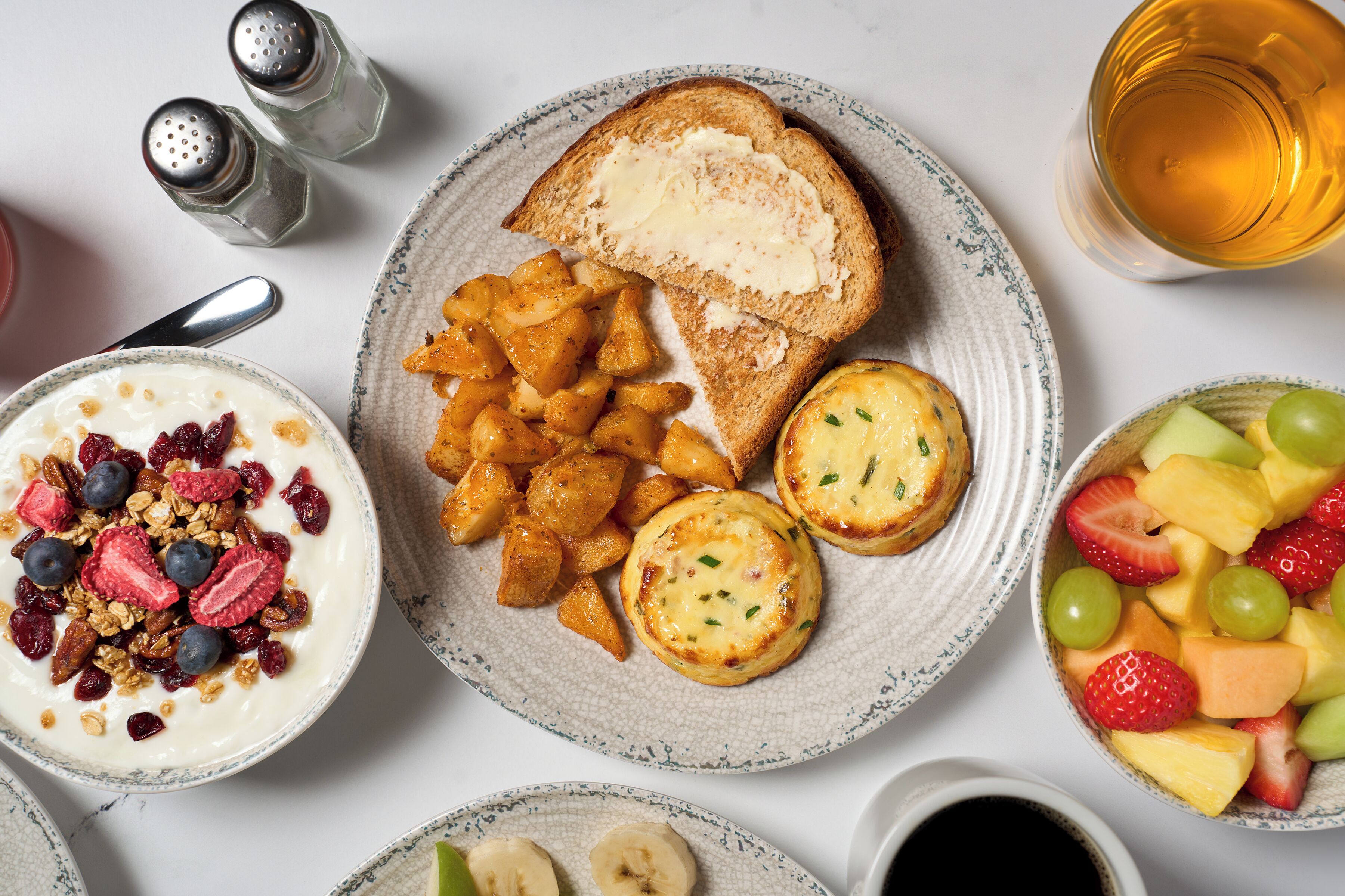 A breakfast setting with toast, fruit, yogurt, and a cup of tea.