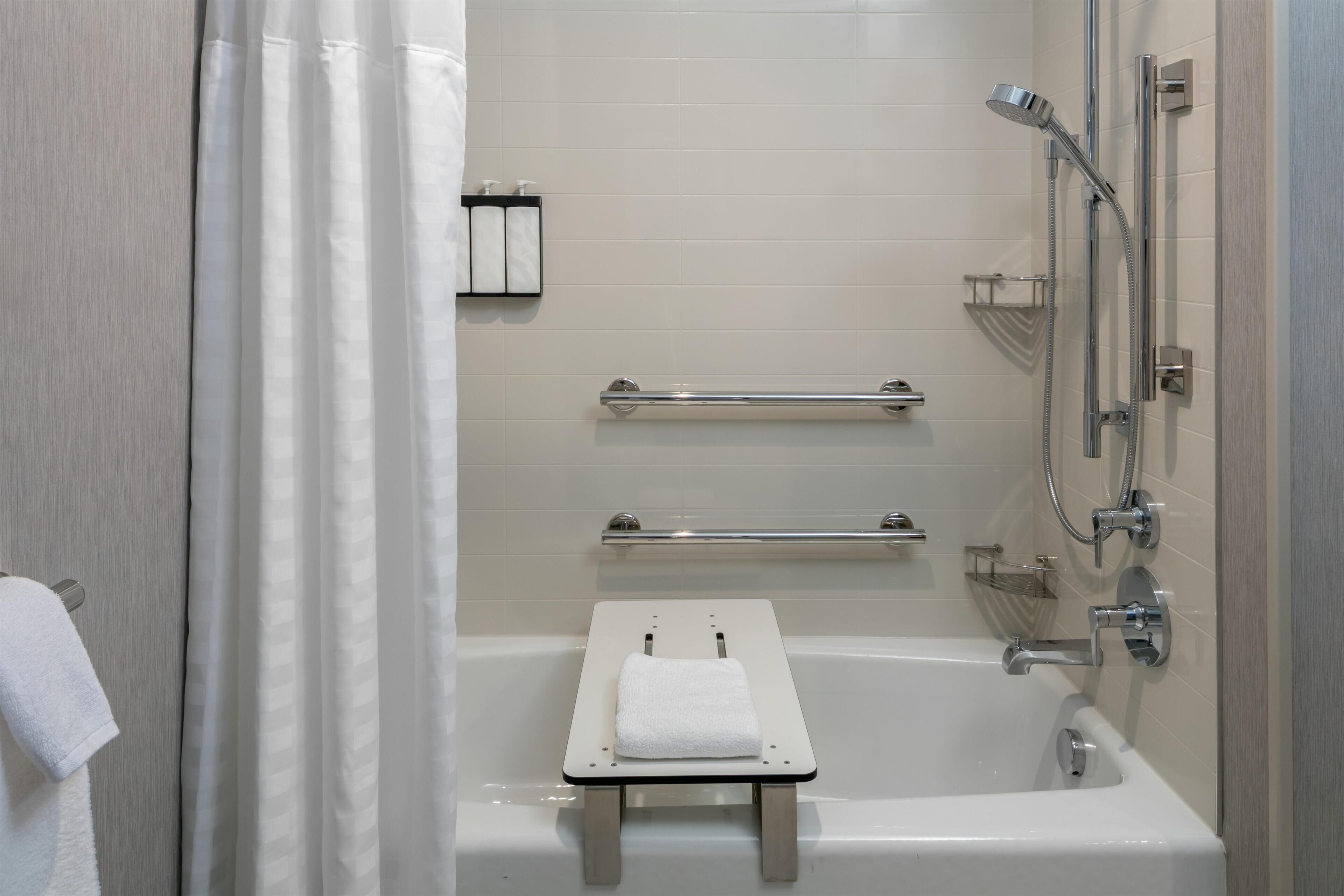 A modern bathroom with a bathtub, a shower, and a towel rack.