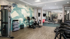 Et fitnessrum med løbebånd, vægte og en spejlvæg.