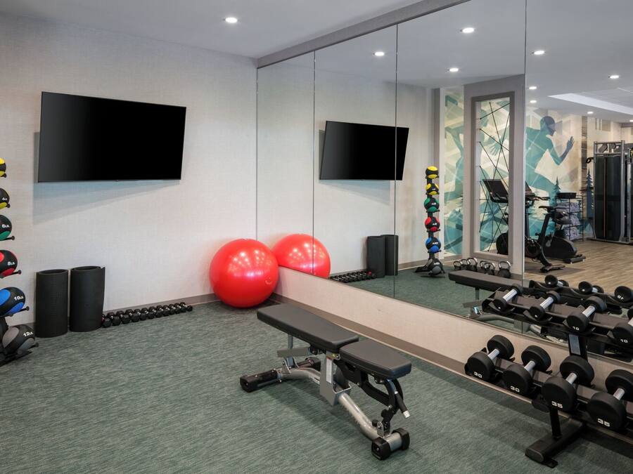 Une salle de sport équipée de matériel d’exercice, d’un banc et d’un grand miroir.