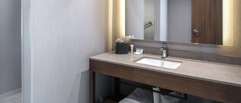 A modern bathroom with a large mirror, a sink, and a towel rack.