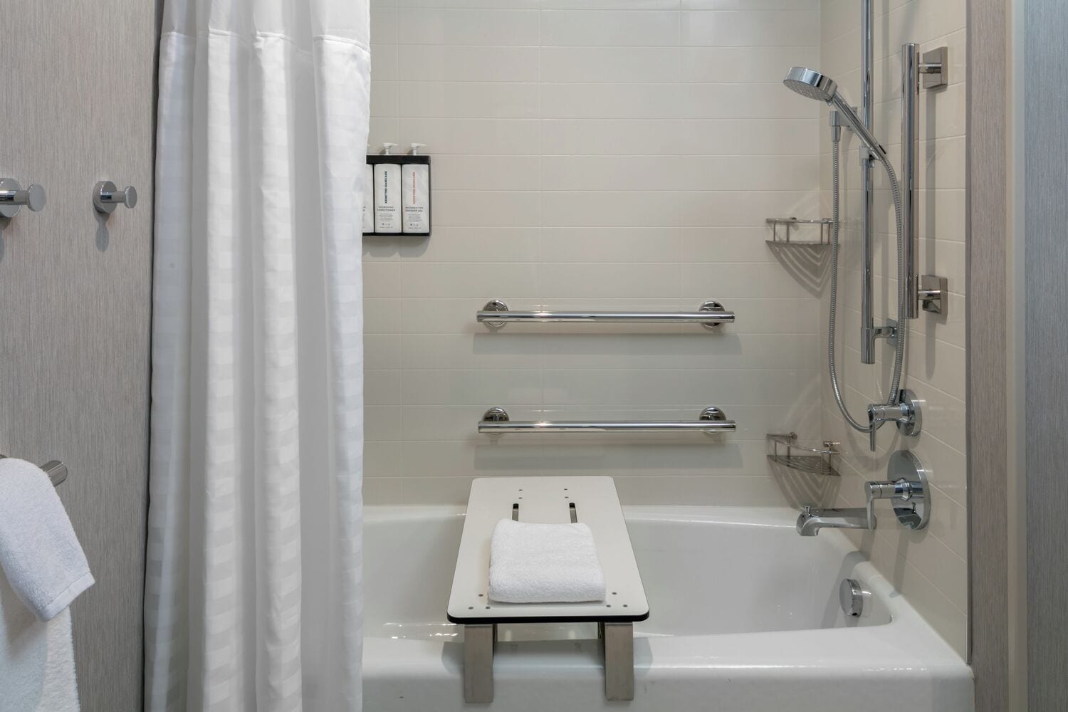 Een moderne badkamer met een bad, douche en handgrepen.
