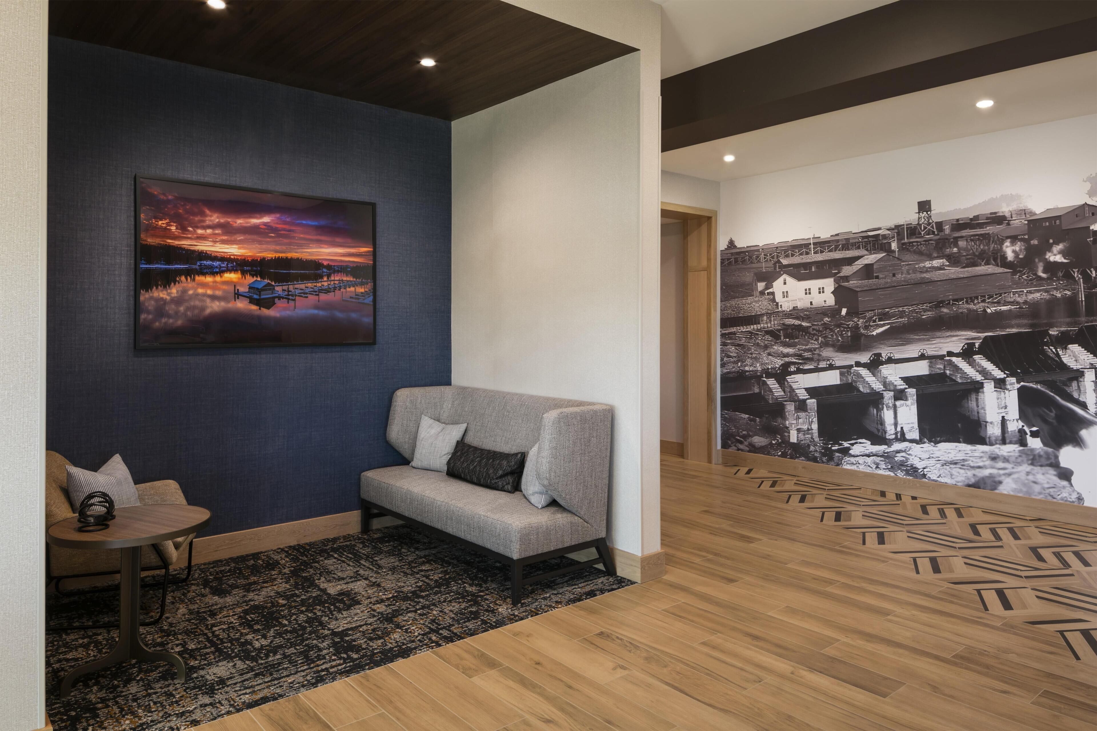 A modern interior with a sofa, a small table, a patterned rug, and a large wall mural.