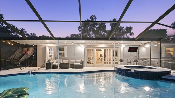 En indendørs swimmingpool med jacuzzi, siddepladser og et fjernsyn.