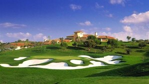 A golf course with sand bunkers and a large house in the background. - Vila Joya (Albufeira)