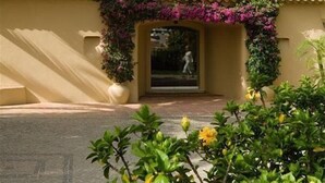 A building with a beige facade, a tiled roof, and a central entrance with a decorative arch. - Vila Joya (Albufeira)