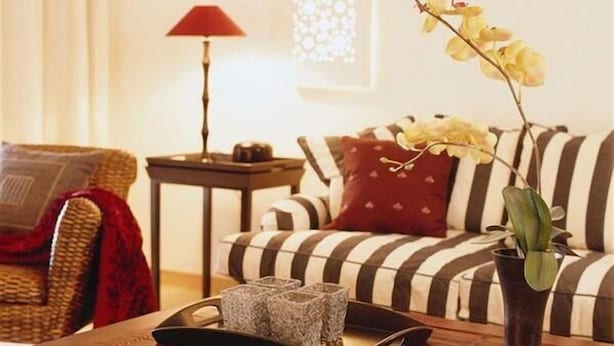 A living room with a wooden coffee table, striped sofa, and a vase with flowers. - Vila Joya (Albufeira)