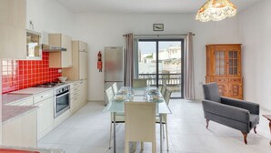 A modern kitchen with a dining area, a view through the glass door, and a wooden cabinet.