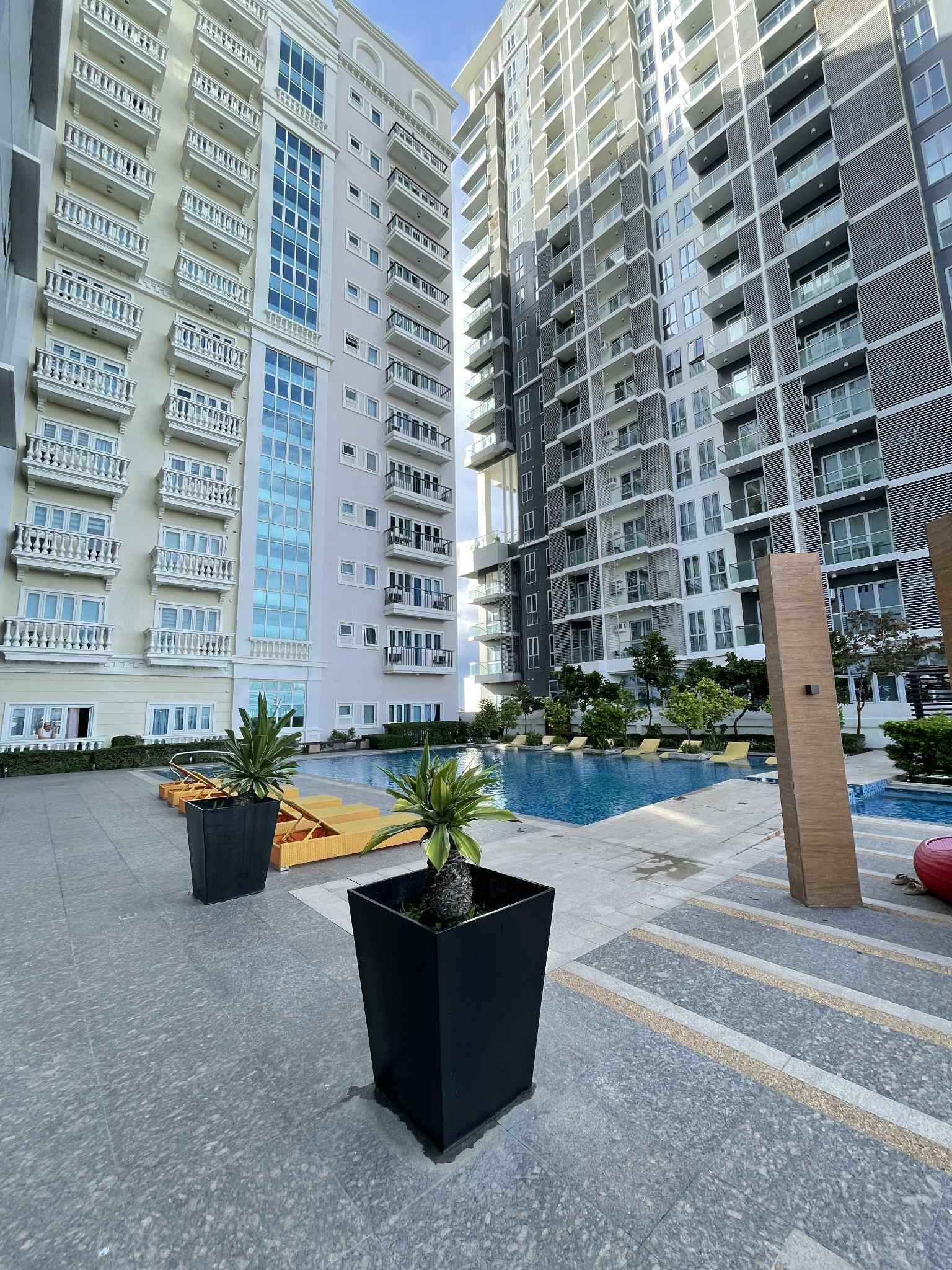 Un immeuble résidentiel moderne doté de nombreux balcons et d’un espace piscine.