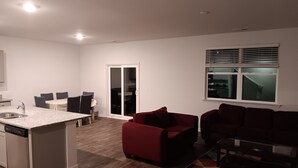 A modern apartment with a kitchen, dining area, and living room. It includes a dishwasher, a dining table with chairs, a red sofa, and a black sofa. - Room with private bathroom for rent for long periods. (Pooler)
